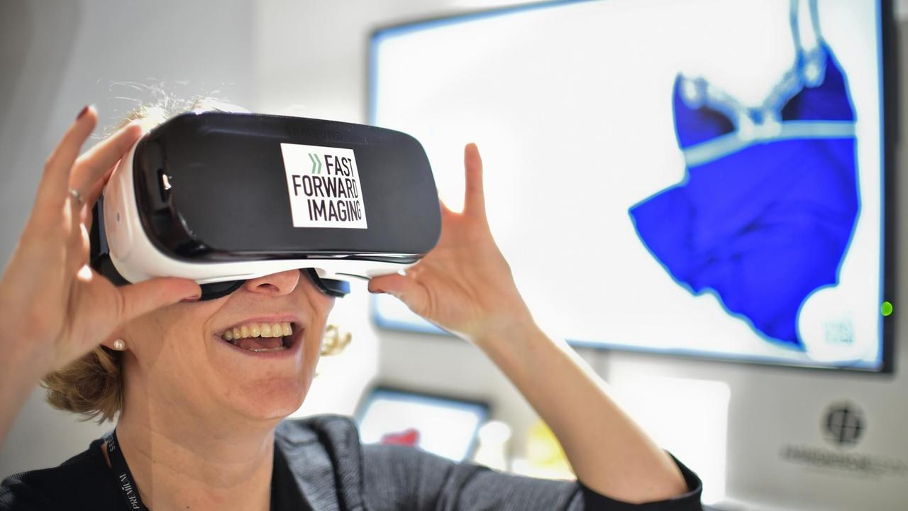 Eine junge Frau geht am 18.01.2017 in Berlin bei der Modemesse Fashiontech im Rahmen der Berliner Modewoche mit Hilfe einer VR-Brille auf digitale Shoppingtour. Foto: Britta Pedersen/dpa-Zentralbild/dpa | Verwendung weltweit