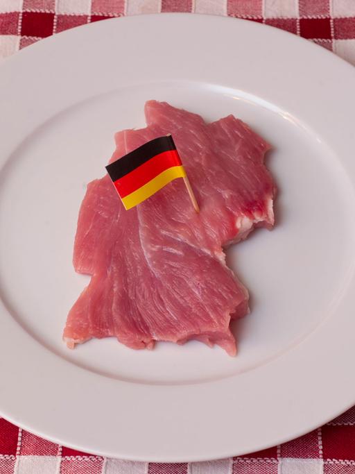 Ein Stück Schweinefleisch, geschnitten wie der Umriss von Deutschland und mit einer kleinen Deutschlandfahne