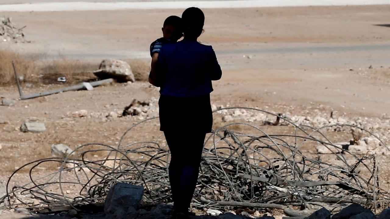 Eine Frau mit ihrem Kind im zerstörten Kobane (Syrien).