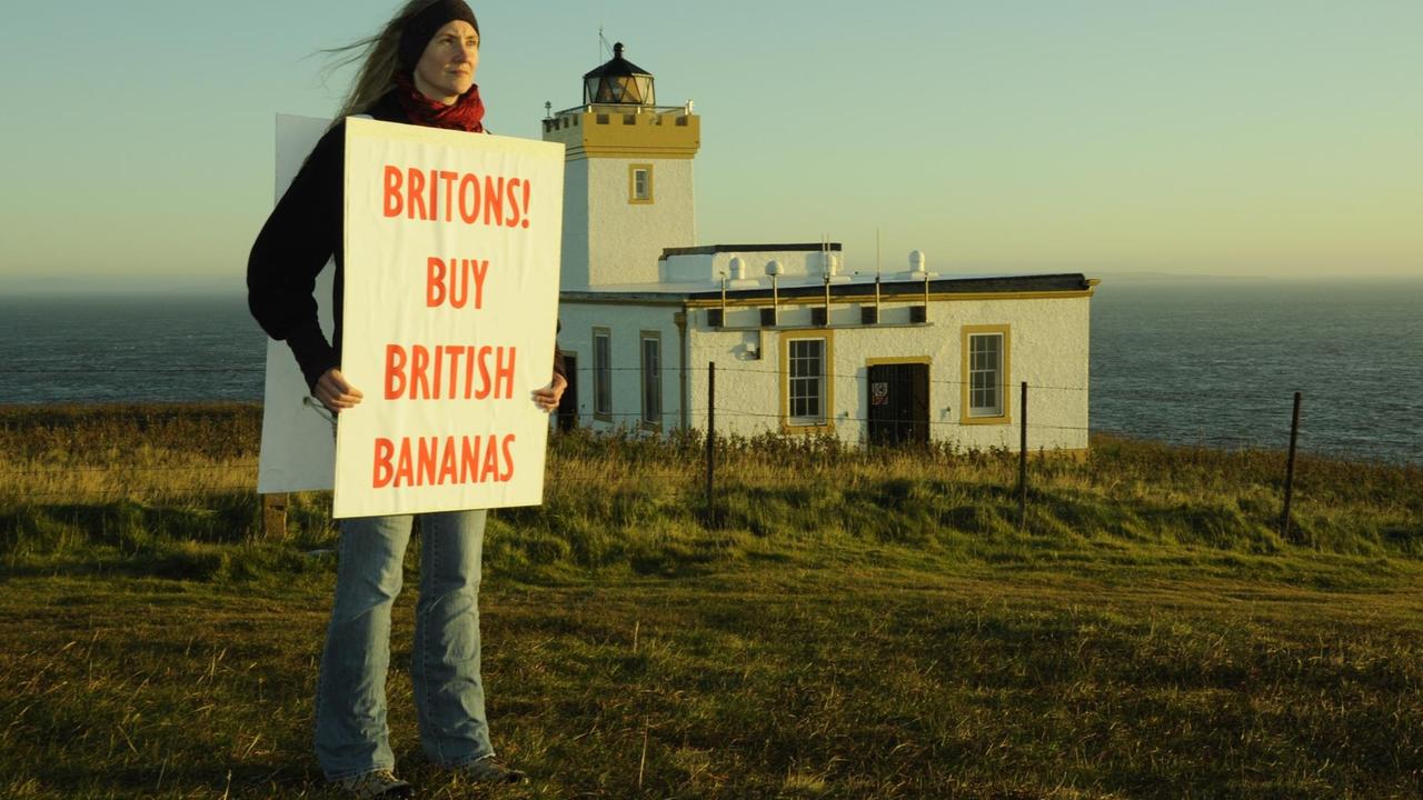 Die aus Deutschland stammende Künstlerin Bibo Keeley bei ihrer Brexit-Kunstperformance in Duncansby Head. Sie hält ein Schild mit der Aufschrift "Britons - Buy British Bananas" in den Händen.