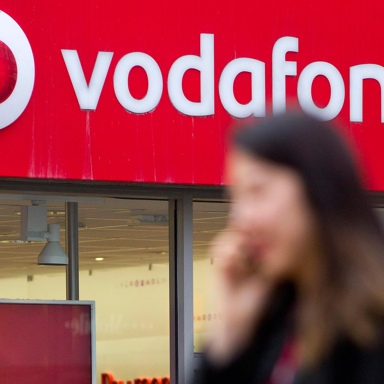 Eien Frau geht telefonierend an einem Vodafone-Shop in London vorbei.