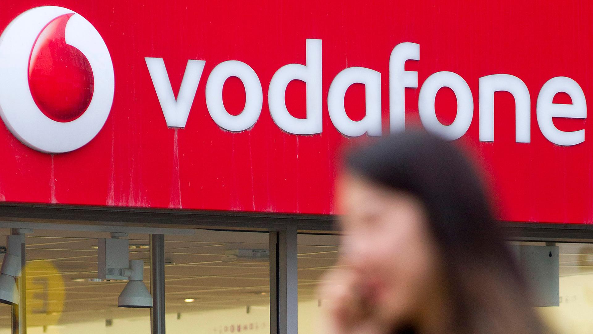 Eien Frau geht telefonierend an einem Vodafone-Shop in London vorbei.