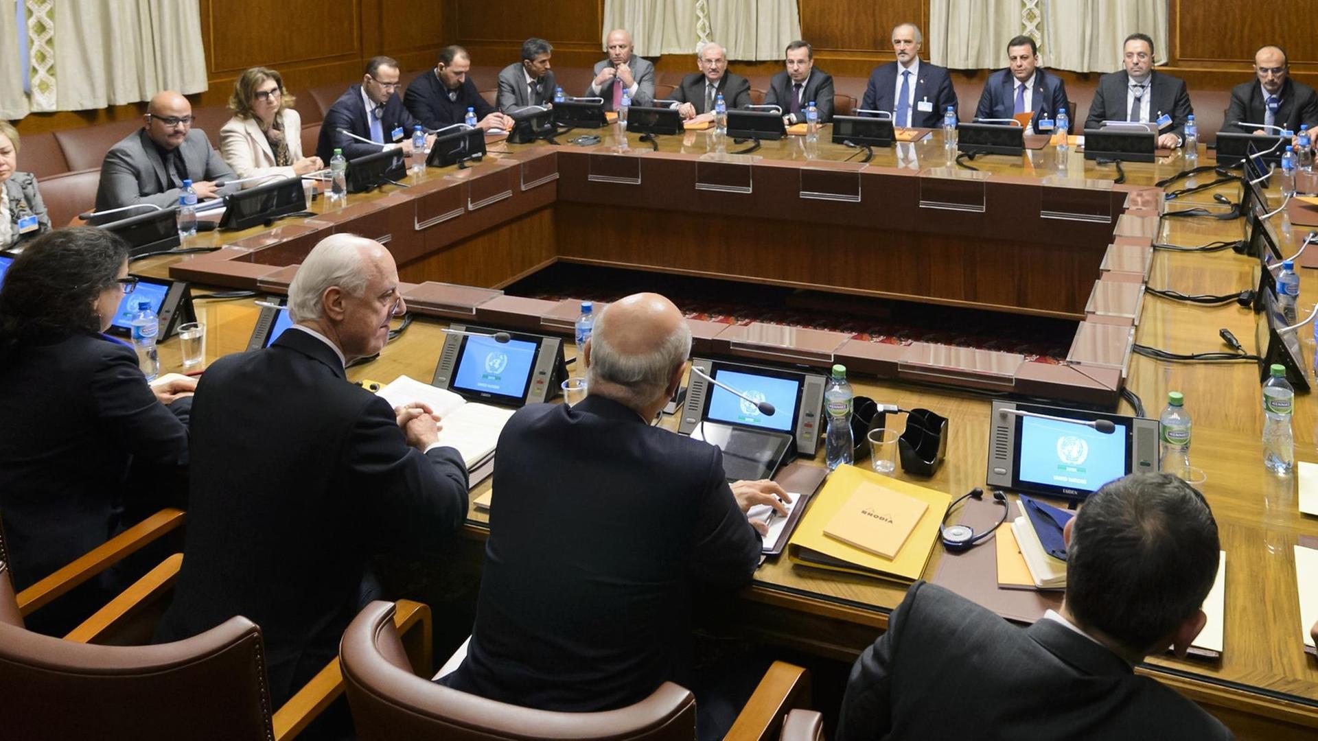 Die Teilnehmer der Syrien-Friedensgespräche sitzen an einem viereckigen Tisch in einem Gebäude der Vereinten Nationen in Genf zusammen. at the opening of Syrian peace talks with the Syrian government delegation at the United Nations (UN) Offices in Geneva