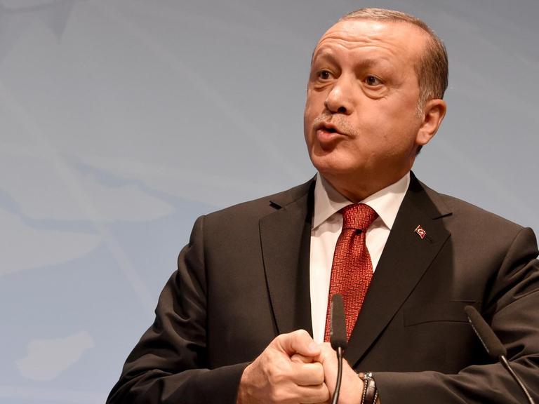 Erdogan spricht auf einer Bühne, seine Hände sind verschränkt.