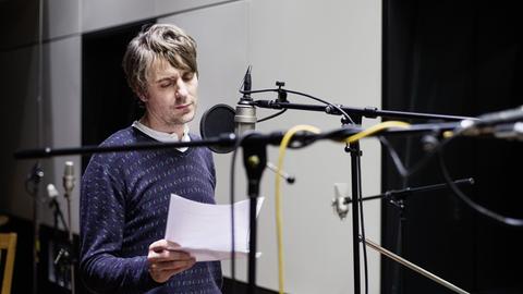 Der Schauspieler Jens Harzer steht im Studio am Mikrofon.