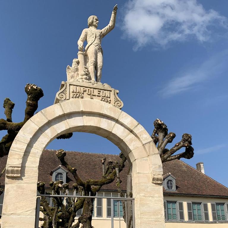 Der Steinbogen vor dem Museum zeigt Napoleon, der  mit dem Finger in Richtung Himmel zeigt