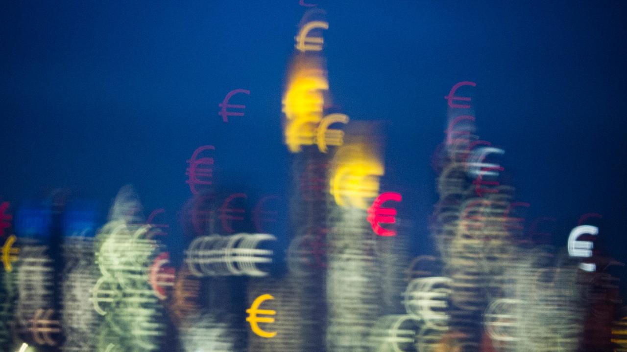 Die Bankentürme von Frankfurt am Main scheinen kurz nach Sonnenuntergang aus vielen kleinen Eurozeichen zu bestehen.