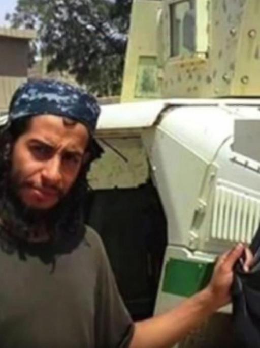 Abdelhamid Abaaoud hält einen Koran und eine IS-Flagge in die Kamera.