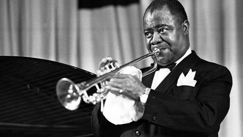 Der amerikanische Jazz-Trompeter und Sänger Louis Armstrong spielt Trompete.