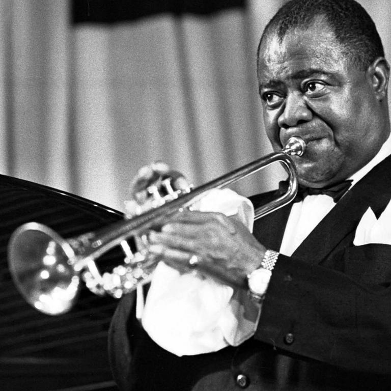 Der amerikanische Jazz-Trompeter und Sänger Louis Armstrong spielt Trompete
