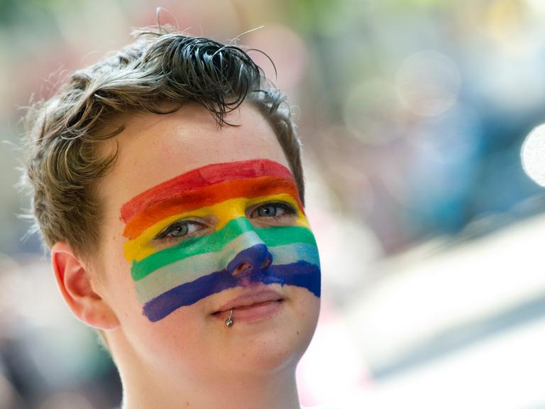 Eine Teilnehmerin des Christopher Street Day hat am 27.07.2013 in Stuttgart eine Regenbogenfahne auf ihr Gesicht gemalt.