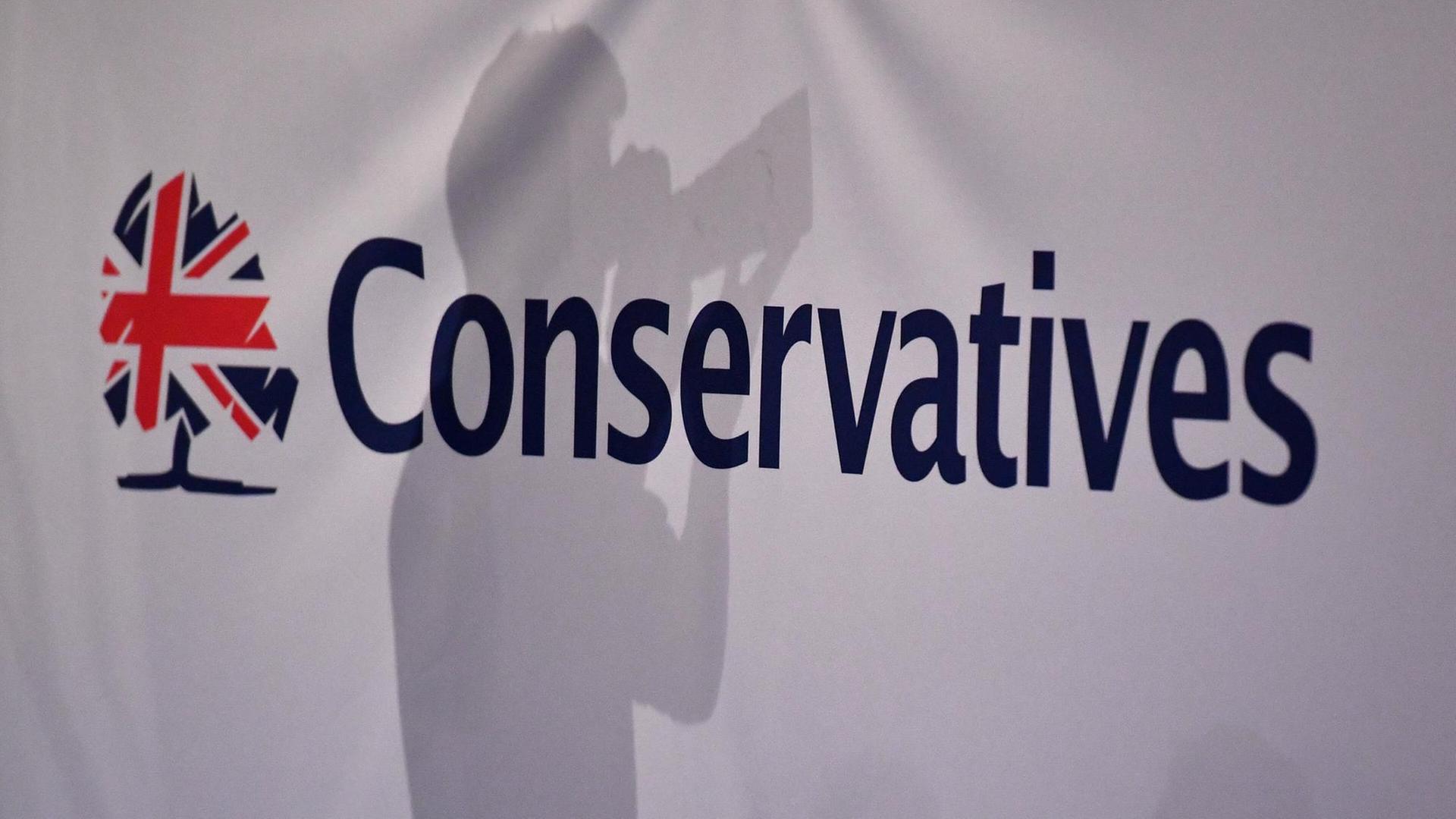 Der Schatten eines Pressefotografen ist vor dem Logo des Parteitags der Konservativen in Großbritannien zu sehen.