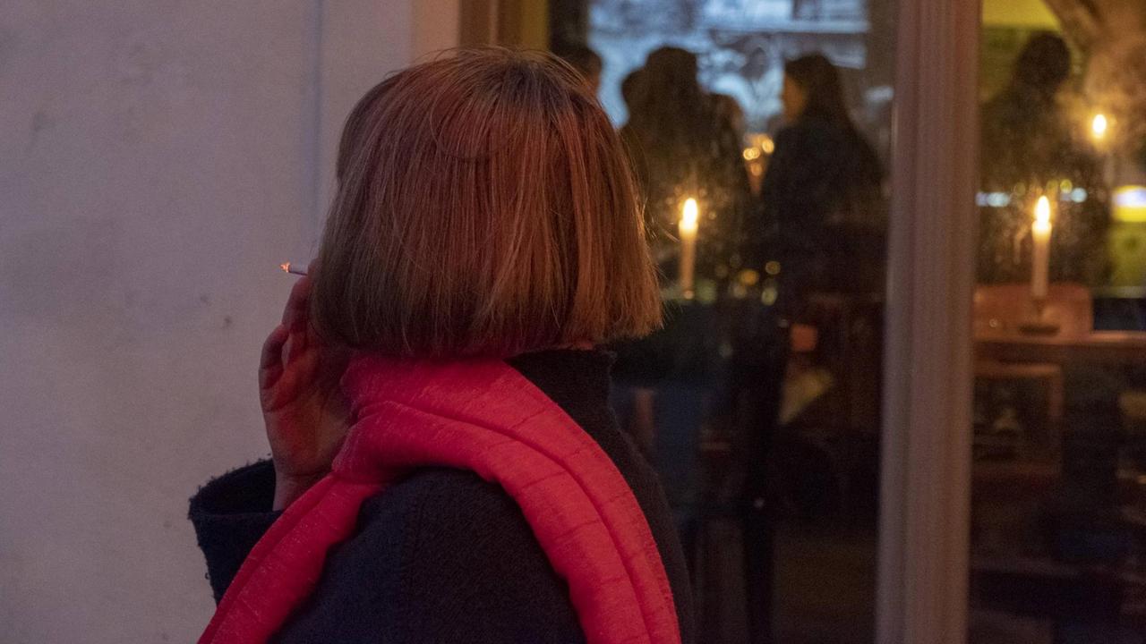 Eine Frau steht vor einer Kneipe in Berlin und raucht eine Zigarette, aufgenommen im Juni 2018.