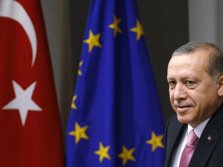 Der türkische Präsident Recep Tayyip Erdogan vor einer türkischen und einer europäischen Flagge.
