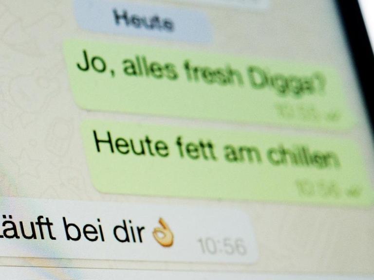 Ein fiktiver Dialog mit dem Satz "Läuft bei dir" ist auf einem Smartphone-Display in dem Messenger WhatsApp zu sehen.