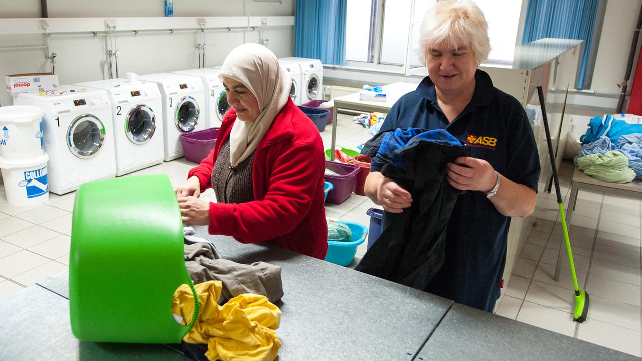 Eine Mitarbeiterin Sabine Schack legt zusammen mit einer Flüchtlingsfrau in Sumte in der dortigen Notunterkunft für Flüchtlinge, Kleidung in der Wäscherei zusammen. 