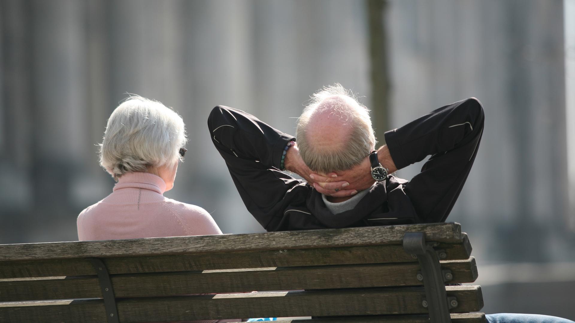 Ein Rentnerpaar genießt die Sonne vor dem Parlament.