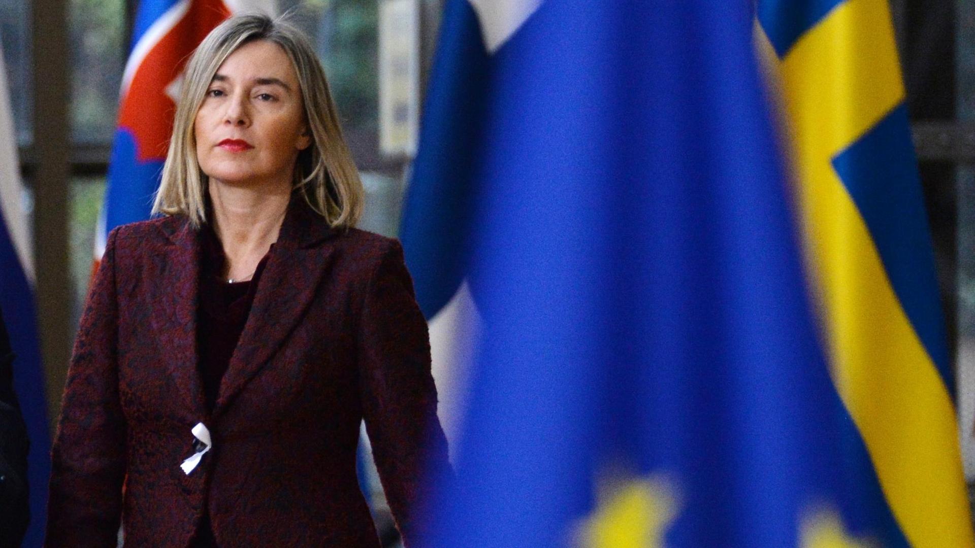 EU-Außenbeauftragte Mogherini mit ernstem Gesichtsausdruck, im Vordergrund schemenhaft die EU-Flagge
