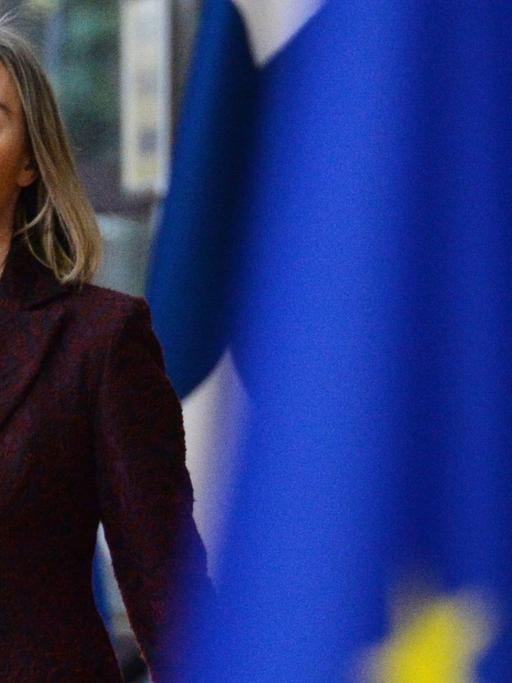EU-Außenbeauftragte Mogherini mit ernstem Gesichtsausdruck, im Vordergrund schemenhaft die EU-Flagge