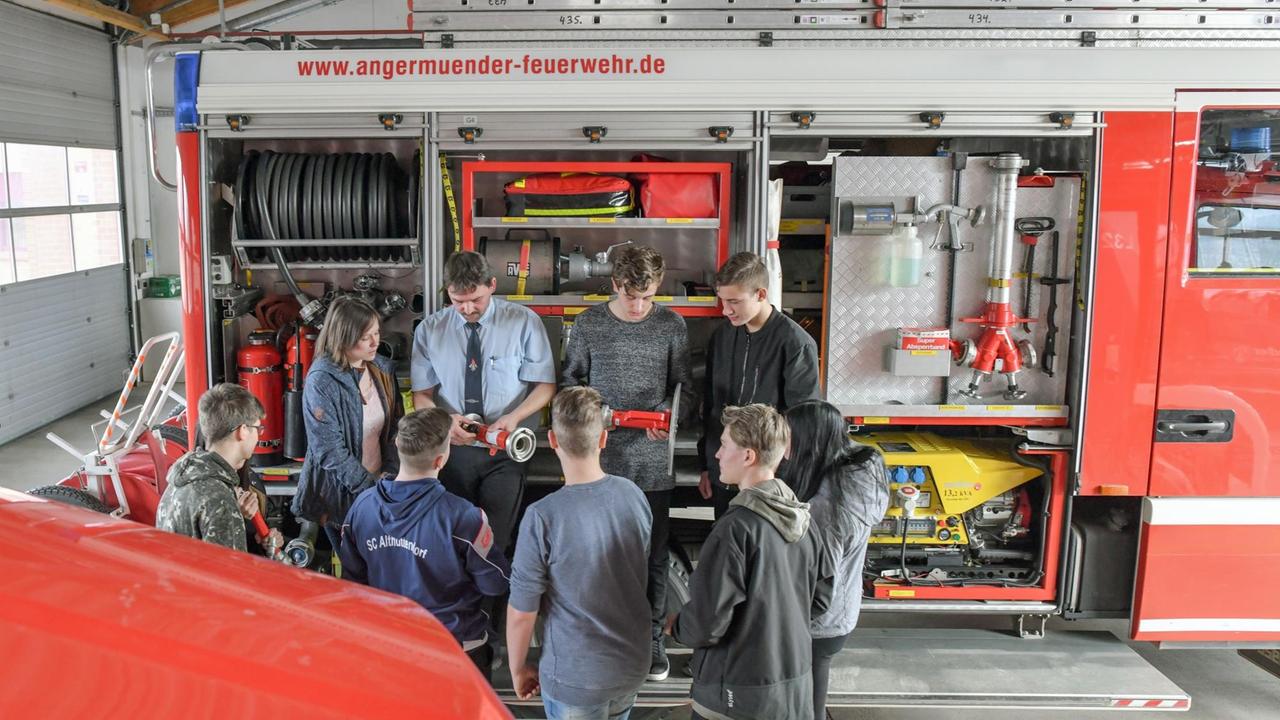 Ein Ausbilder bei der Freiwilligen Feuerwehr Angermünde, unterrichtet Neuntklässler im Wahlpflichtfach Feuerwehrausbildung an einem Löschfahrzeug.