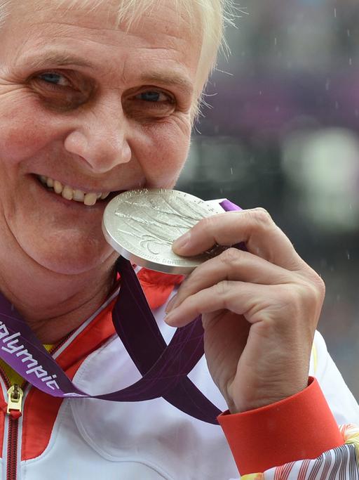Die Leichtathletin Marianne Buggenhagen lächelt in die Kamera und zeigt ihre Silber-Medaille