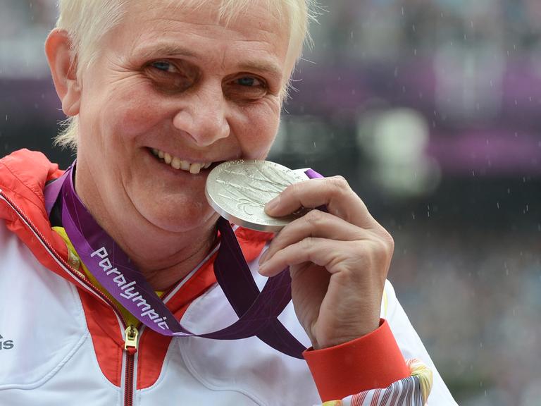 Die Leichtathletin Marianne Buggenhagen lächelt in die Kamera und zeigt ihre Silber-Medaille