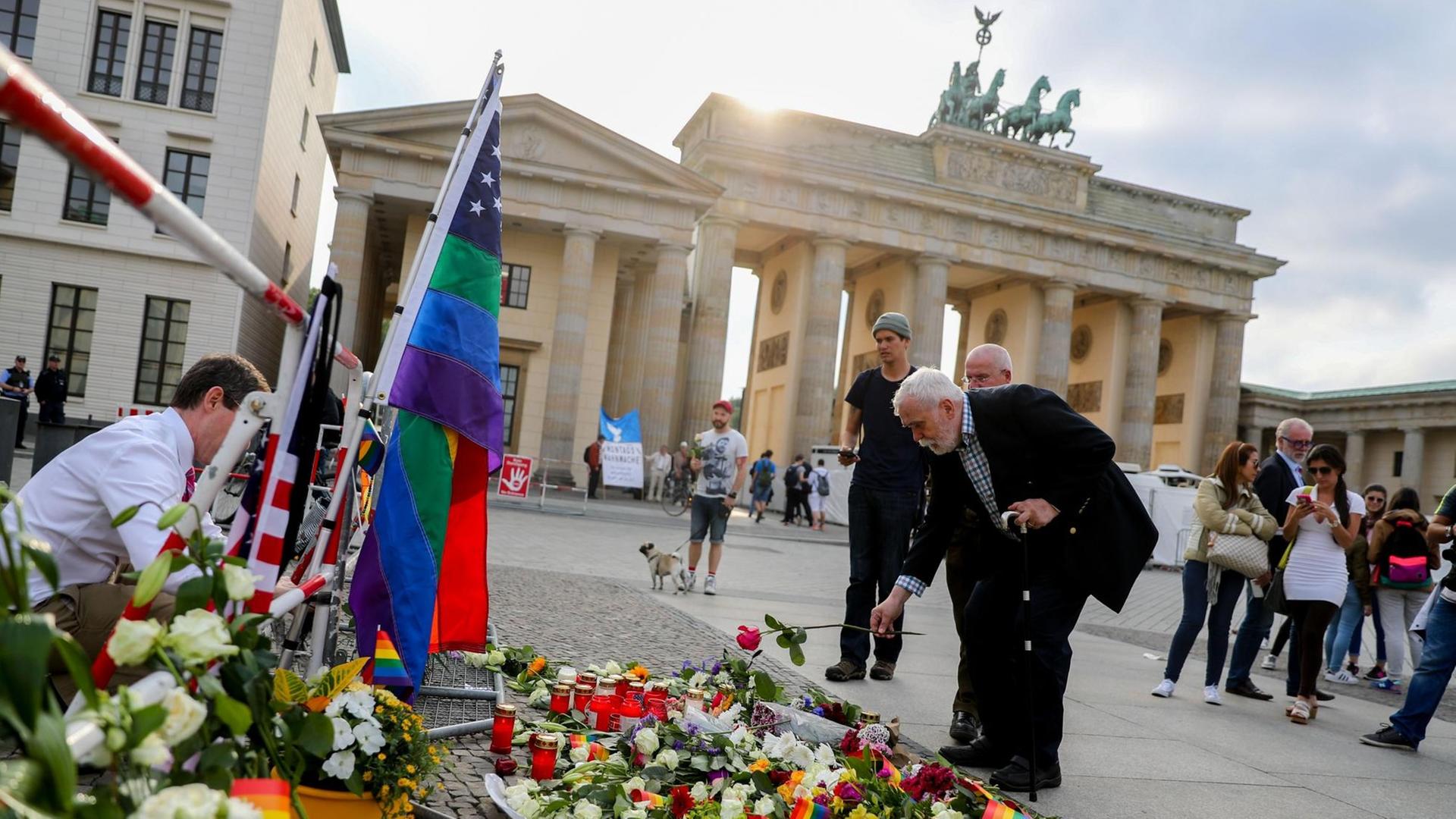 Passanten legen am 13.06.2016 in Berlin vor der Botschaft der USA am Brandenburger Tor im Gedenken der Opfer des Attentats in Orlando Blumen nieder.