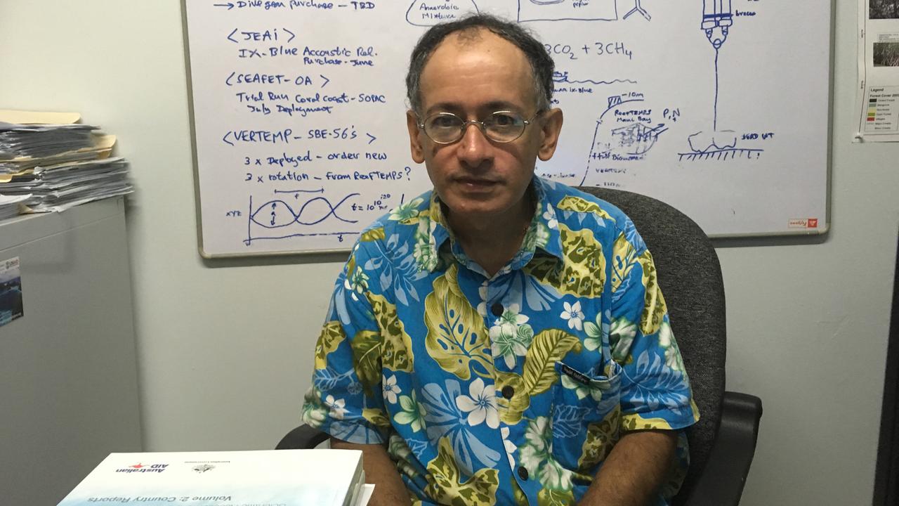 Der fidschianische Klimawissenschaftler Antoine de Ramon N'Yeurt sitzt in seinem Büro vor einer Tafel mit Formeln und Zeichnungen von chemischen Prozessen.