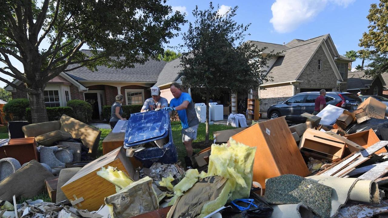 Einwohner von Houston stehen vor einem Berg beschädigter Möbel und Gegenstände auf der Straße