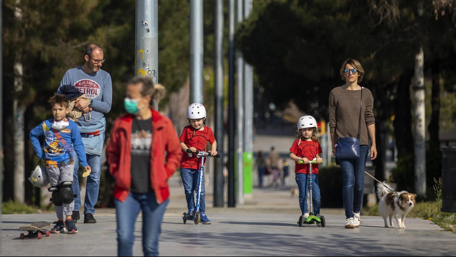 Erwachsene und Kinder gehen in Barcelona in einer Allee spazieren.