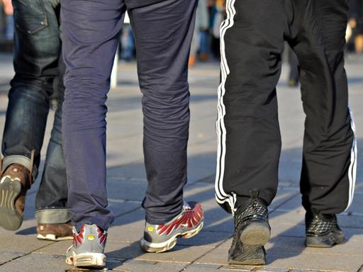 Das Bild zeigt die Beine der drei, nur einer von ihnen trägt eine Jogginghose.