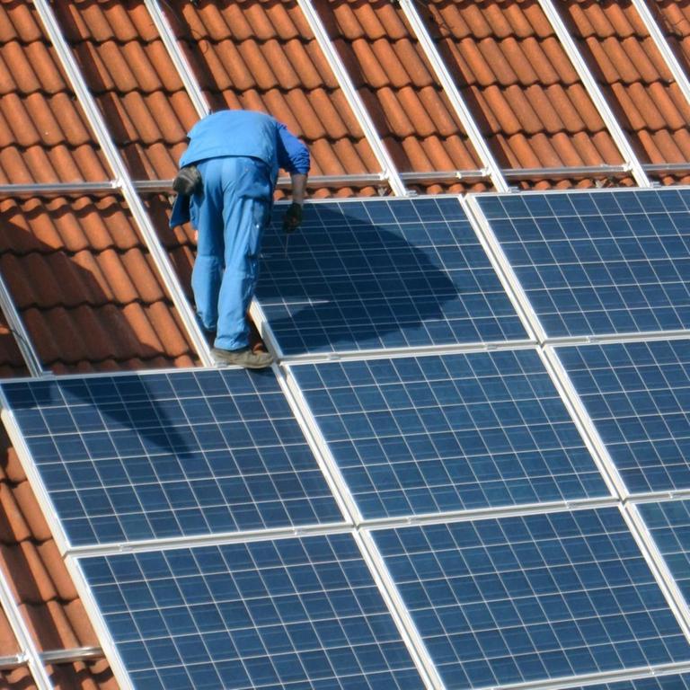 Arbeiter montieren Solarzellen auf einem Dach