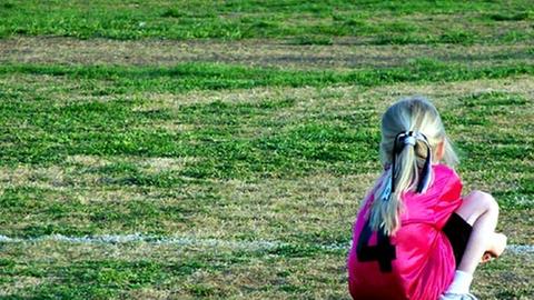 Ein kleines Mädchen wartet am Rande des Spielfeldes auf seine Einwechselung.