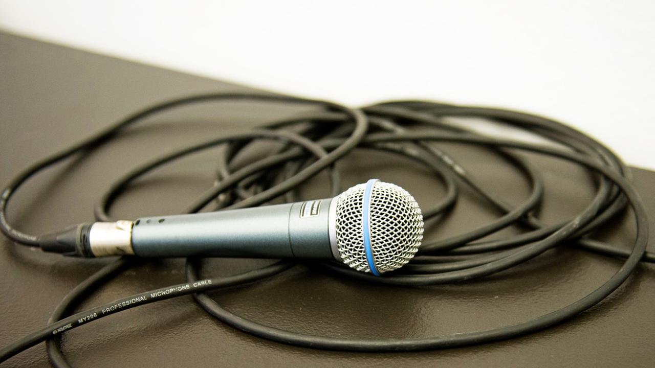 Ein Mikrofon mit langem Kabel liegt auf einem Podest. 