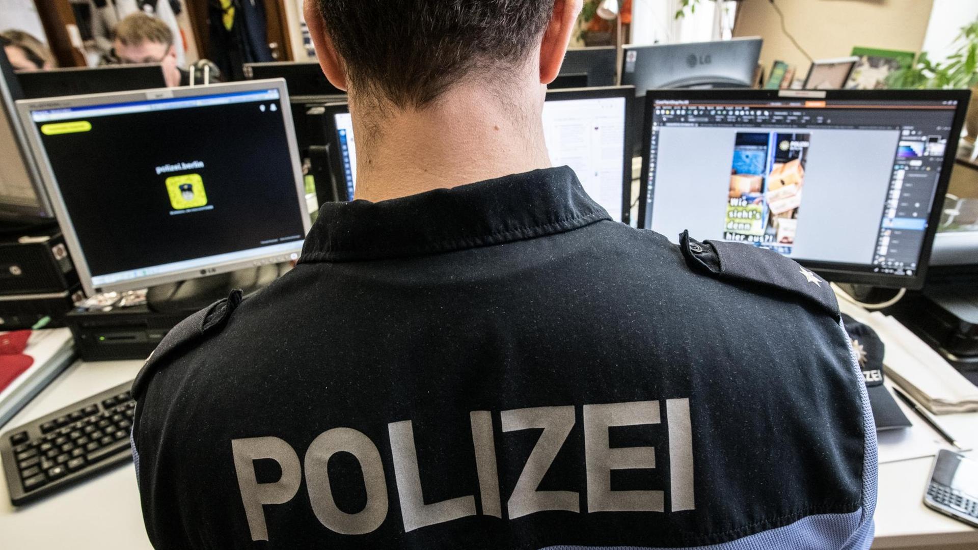 Ein Mitarbeiter des Social Media Teams der Polizei sitzt in einem Raum im Polizeipräsidium vor seinen Computern.