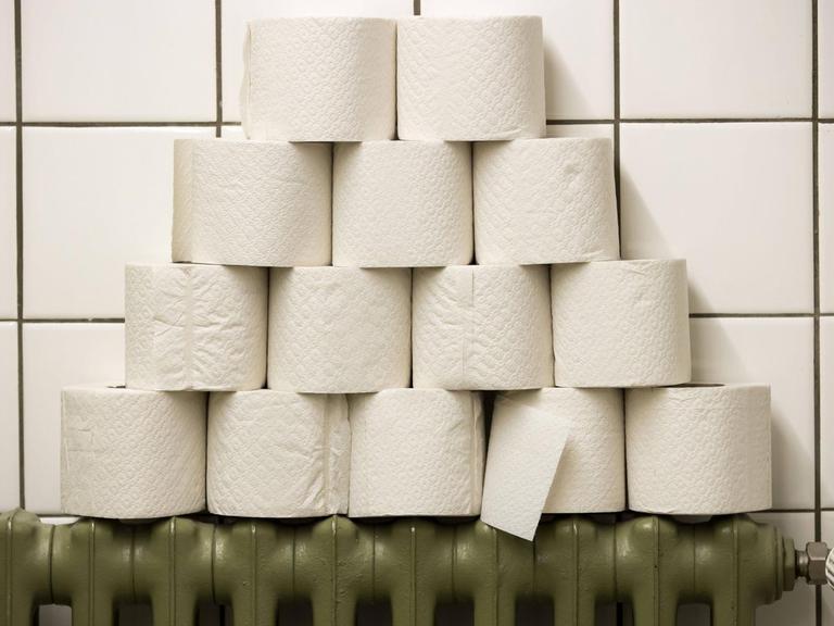 Gestapelte Toilettenpapierrollen auf dem Heizkörper einer öffentlichen Toilette