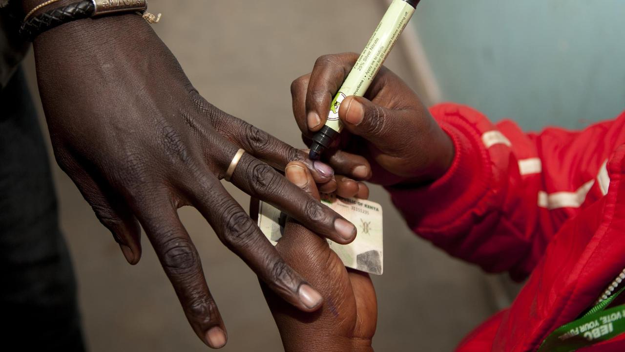 Eine Wahlhelferin markiert am 08.08.2017 in Nairobi (Kenia) in einem Wahllokal den Finger eines Wählers, nachdem dieser seine Stimme abgegeben hat.