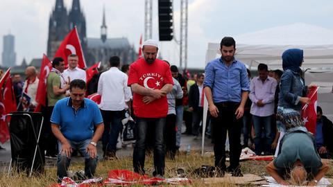 Anhänger des türkischen Staatspräsidenten Erdogan beten am 31.07.2016 in Köln (Nordrhein-Westfalen) vor der Kundgebung