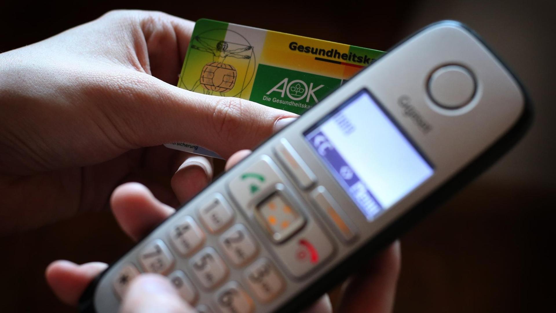Ein Mann hält eine Gesundheitskarte in der Hand, während er am Telefon eine Nummer wählt.