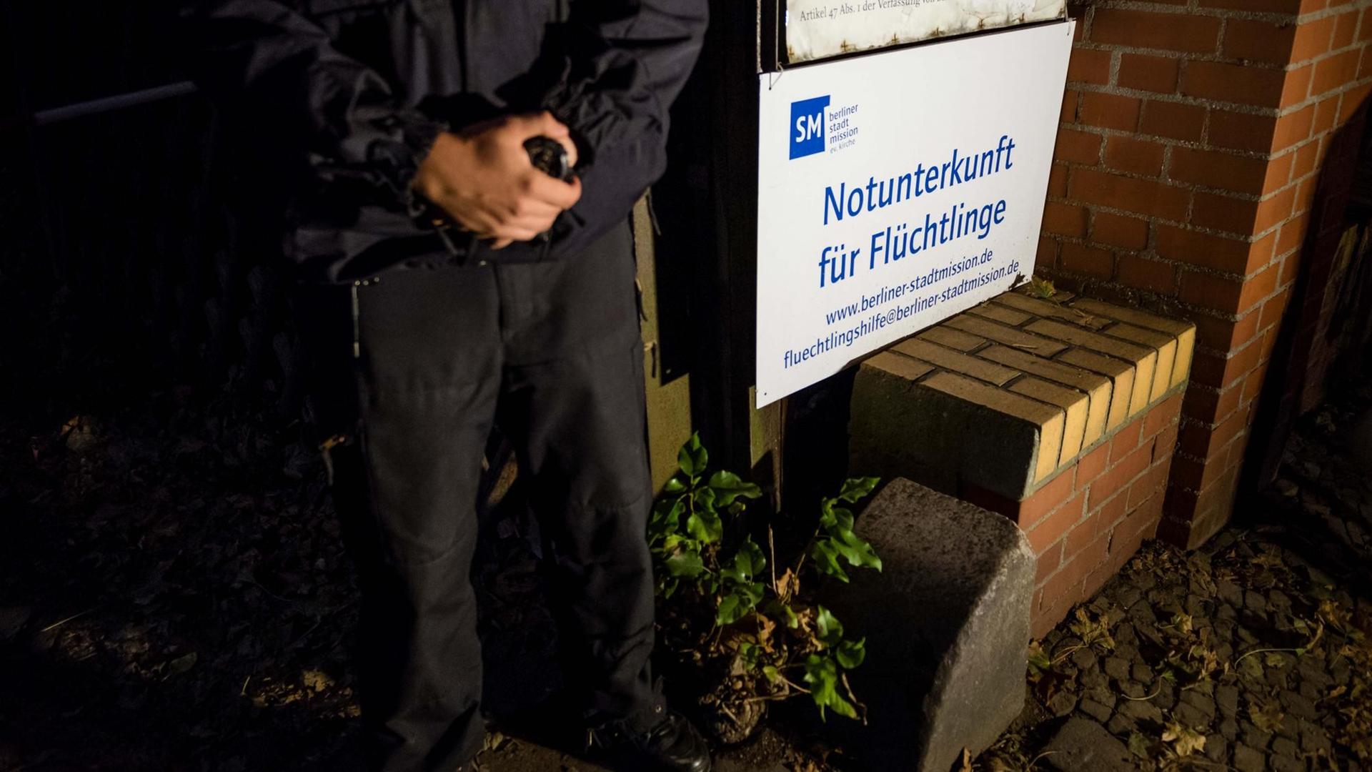 Ein Polizist der Berliner Polizei steht am 28.09.2016 neben einem Eingangsschild einer Flüchtlingsunterkunft in der Kruppstraße in Berlin-Moabit.