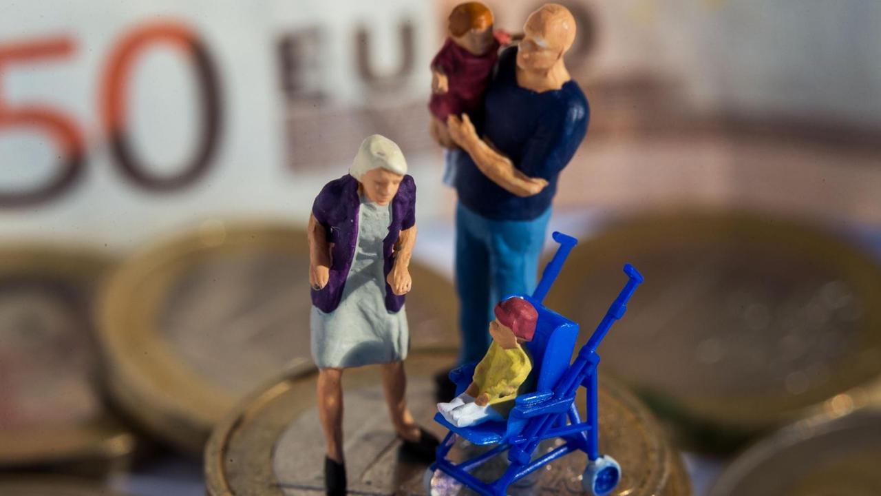 Das Bild zeigt Miniaturfiguren (Mutter, Vater mit Kind im Arm, ein weiteres Kind im Buggy) auf einem Stapel von Euro-Geldmünzen. Im Hintergrund sieht man unscharf einen 50-Euro-Schein.