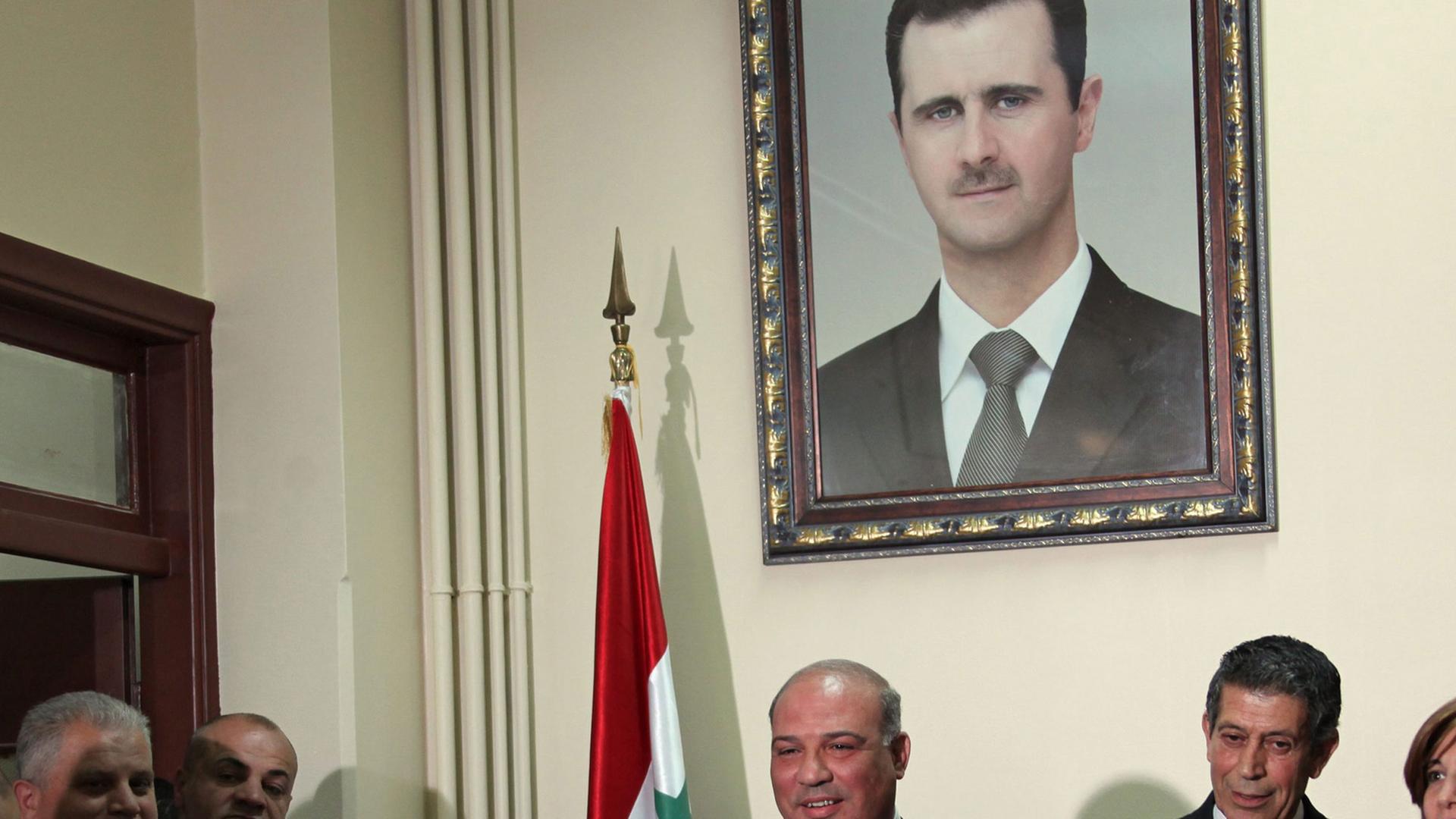 Ein Sprecher des Verfassungsgerichts gibt unter einem Assad-Portrait eine Pressekonferenz.