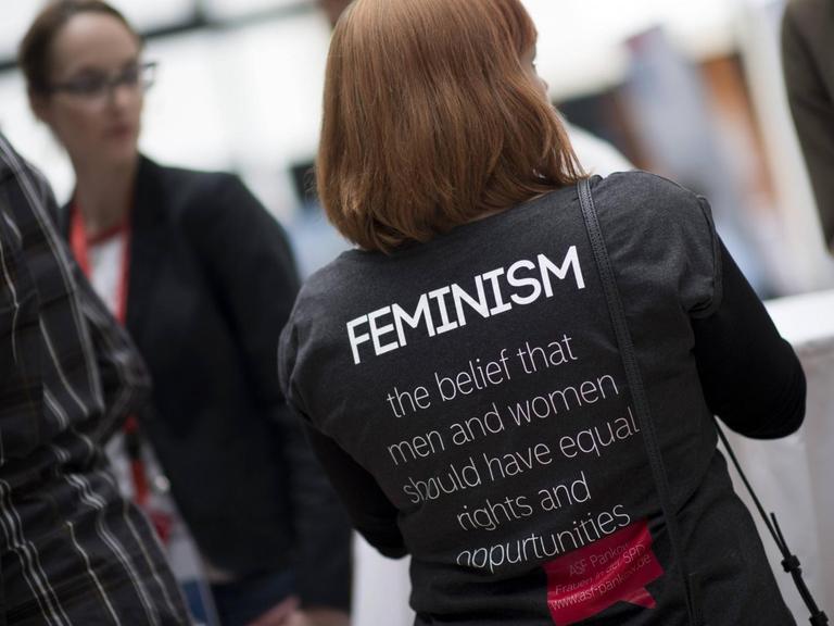 Frau mit schwarzem T-Shirt und Aufdruck "Feminism"