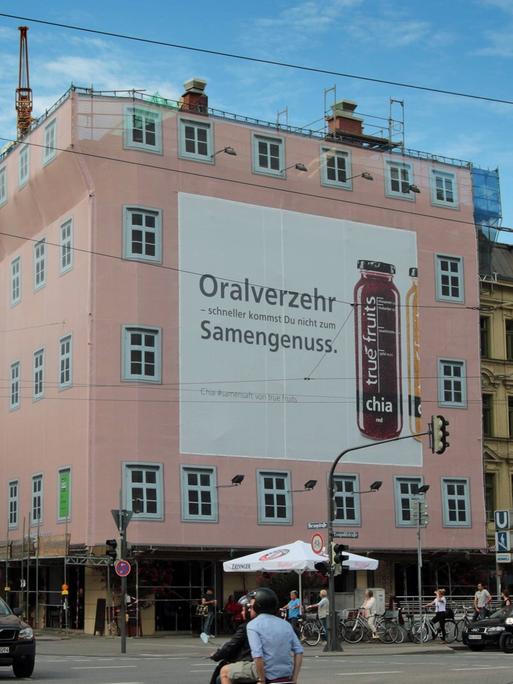 Ein großflächiges Werbeplakat für Chia True Fruits mit der Aufschrift "Oralverkehr - schneller kommst Du nicht zum Samengenuss" hängt an einem Haus in München.
