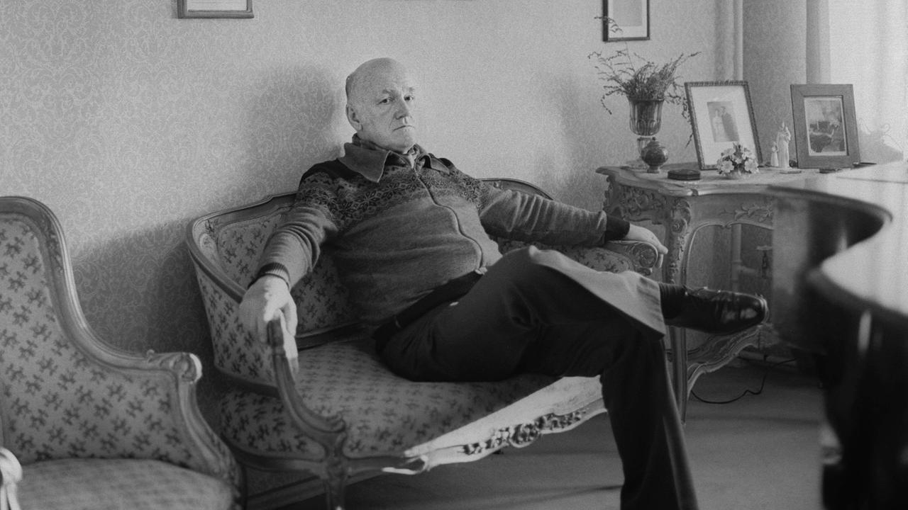 Der Pianist Swjatoslaw Richter sitzt in einem Wohnzimmer auf einer Couch. 