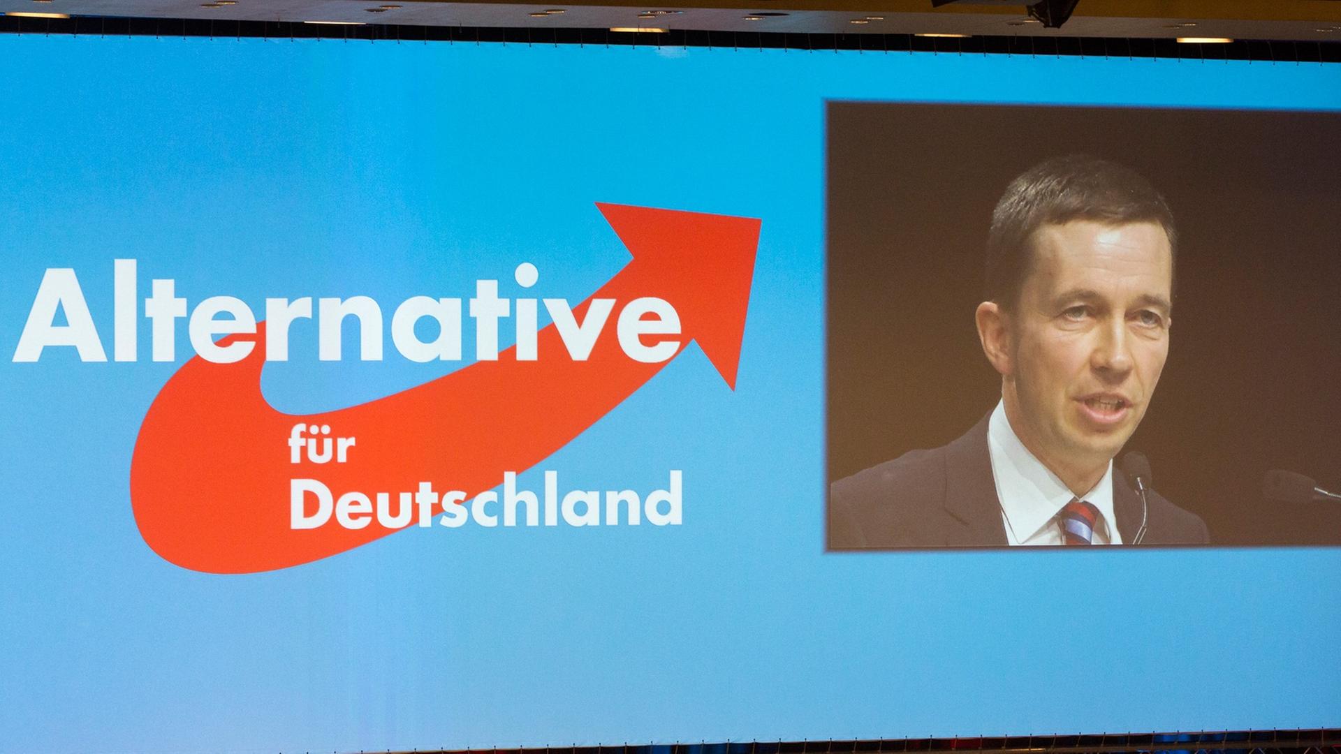 Leinwand mit dem Logo der AfD und einem Bild der Videoübertragung der Rede von Bernd Lucke.
