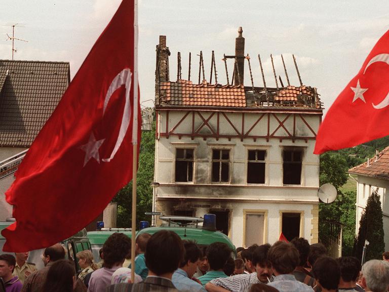 Demonstranten tragen am 29. Mai 1993 vor dem ausgebrannten Haus in Solingen türkische Fahnen.