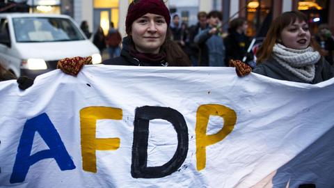 Eine Demonstrantin hält ein Laken mit der Aufschrift "AFDP" in die Höhe.