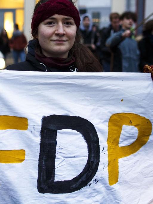 Eine Demonstrantin hält ein Laken mit der Aufschrift "AFDP" in die Höhe.