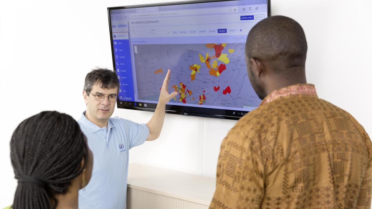 Der Epidemiologe Professor Gérard Krause erklärt zwei Mitarbeitern das SORMAS-Dashboard, ein Tool zur Überwachung von Infektionsausbrüchen